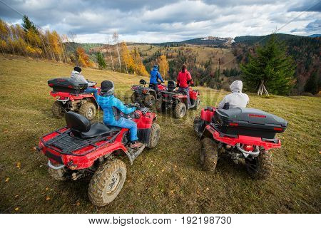 Rear View Group Of Five Person Riding Quad Bikes On Hill And Enjoying Beautiful Autumn Scenery Of Co