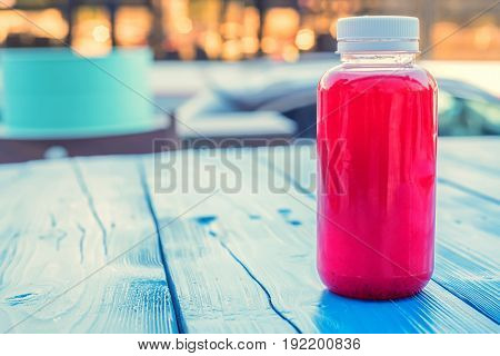 Close up soft fruit strawberry drink in plastic bottle on wooden table in outdoors restaurant