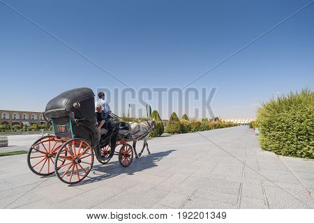 ISFAHAN IRAN - OCTOBER 22 2016 : Tourists sit on carriage during visit the Naghsh-e Jahan Square (Imam Sqaure) UNESCO World Heritage Sites in Isfahan (Esfahan) Iran.
