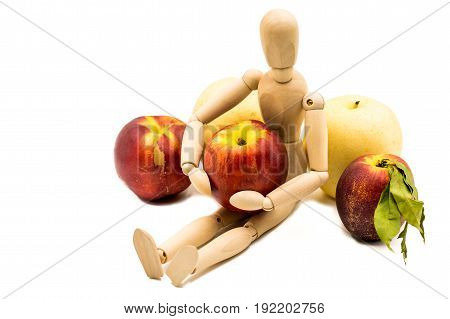 wooden man puppet sitting hugging a nectarine on white background
