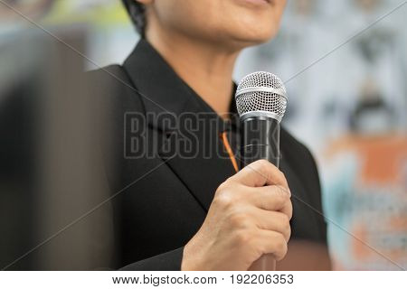 blurred smart businesswoman speech with microphone in meeting room at conference hall