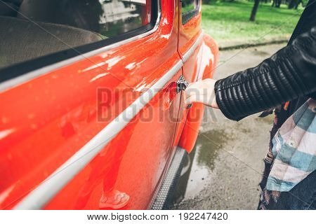 woman hand opens door of red old retro car