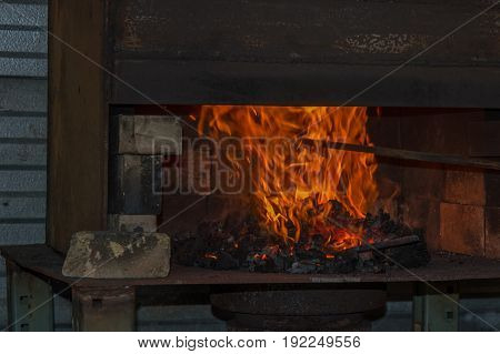A fire blazes hot in the coal forge in the bladesmith shop