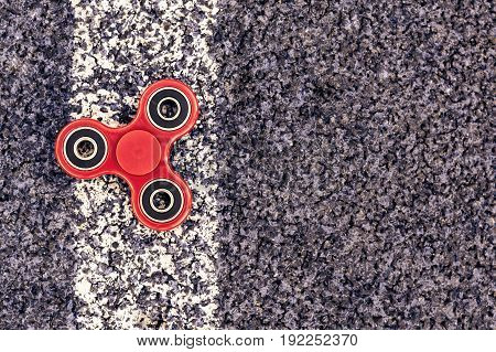 Popular spinner gadget in 2017 on a blue and white background. Modern red plastic spinner fidget game for young people.