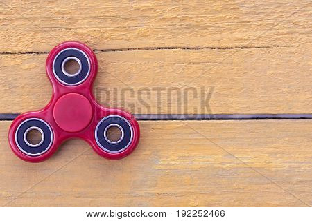 Top view of the new red spinner gadget in 2017 on a yellow wooden background