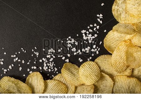 Crinkle cut potato chips on kitchen table. Tasty spicy potato chips with salt.Top view
