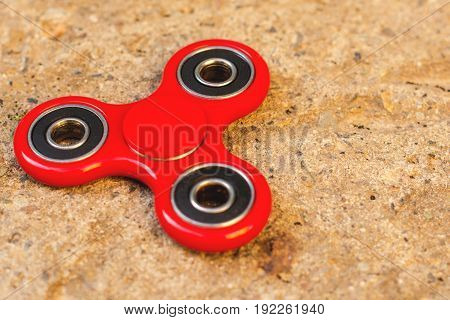Top view of the popular red spinner gadget in 2017 on a concrete background. popular red fidget spinner toy