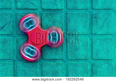 Top view of the popular red spinner gadget in 2017 on the blue-green background. Popular spinner gadget in 2017.