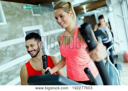 Attractive woman working cardio exercises with personal trainer in gym