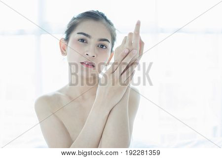 A beautiful woman asian using a skin care product moisturizer or lotion taking care of her dry complexion. Moisturizing cream in female hands .