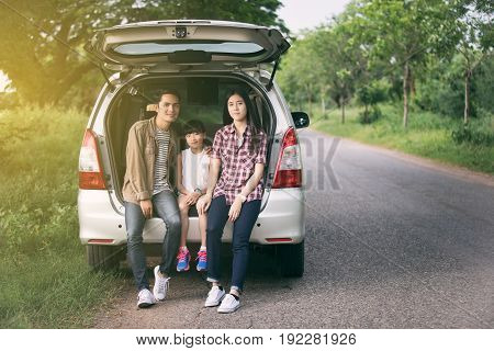 happy little girl with asian family sitting in the car for enjoying road trip and summer vacation