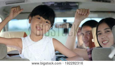 happy little girl with asian family sitting in the car for enjoying road trip and summer vacation
