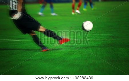 Soft focus and blurry of Soccer player kicking ball in action at stadium