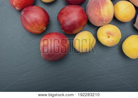 Ripe apricot and nectarine on black background of slate or stone.