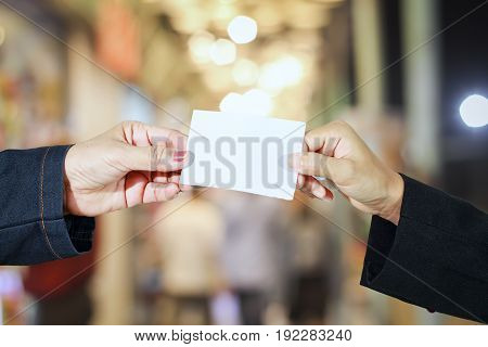 businesswoman asian holding and shown a business card on local market and supermarket/mall blur for background and shopping
