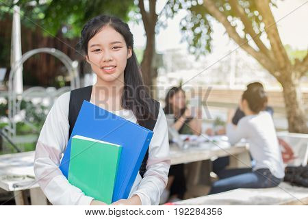 Asian student girl holding book on campus