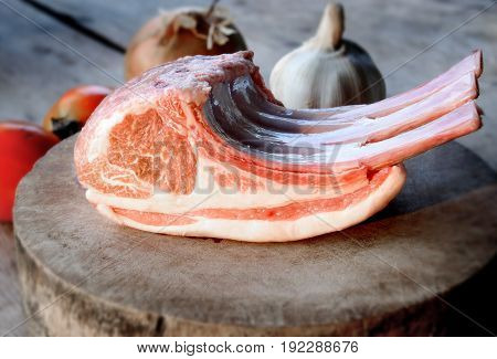Raw lamp rib on wooden plate in the kitchen with low sun lighting.