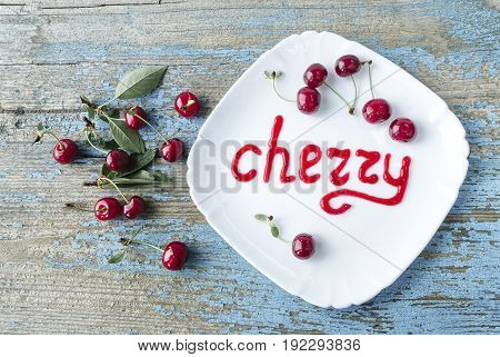 Sweet cherry in white plate on old wooden table Inscription from cherry jam