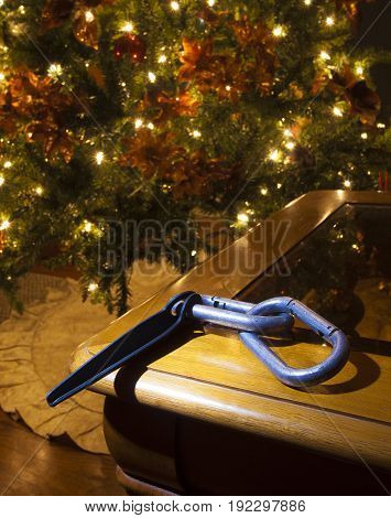 Piton and carabiners on a table with a Christmas tree behind