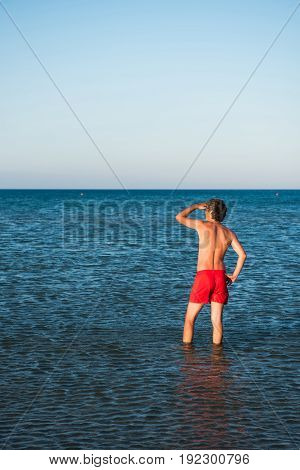 Slim Guy Posing In Red Swimwear In Sea Water