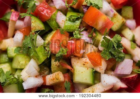 Indian Green Salad also known as Kachumber is a colourful salad dish in Indian cuisine consisting of fresh chopped tomatoes, cucumbers, onions, and sometimes, chili peppers. selective focus