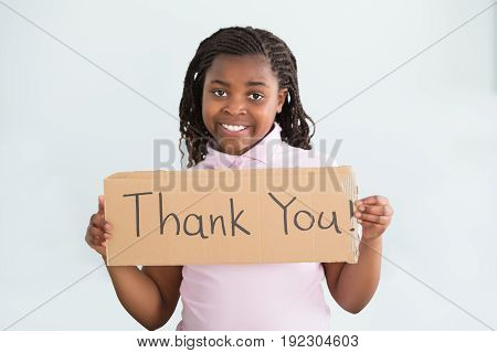 Close-up Of A Smiling African Girl Holding Thank You Sign Against White Background