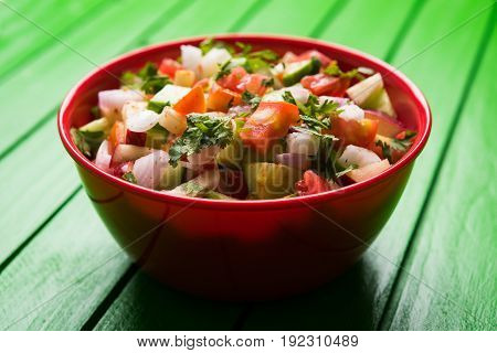 Indian Green Salad also known as Kachumber is a colourful salad dish in Indian cuisine consisting of fresh chopped tomatoes, cucumbers, onions, and sometimes, chili peppers. selective focus