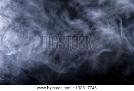 Smoke from a Vape with light effects on a black background. The image is an abstract texture with copy or text space. It has patterns showing movement and depicts a spooky mood with a Halloween theme.