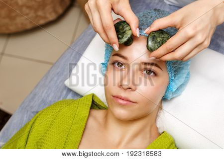 Spa treatment. Facial massage with jade stones. Alternative medicine. Massage of forehead zone. Guasha