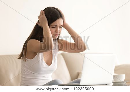 Young attractive woman suffering from a sudden attack of headache or dizziness during work on laptop at home. Stressed teenager girl feeling chronic fatigue, nervous tension, symptoms of sickness