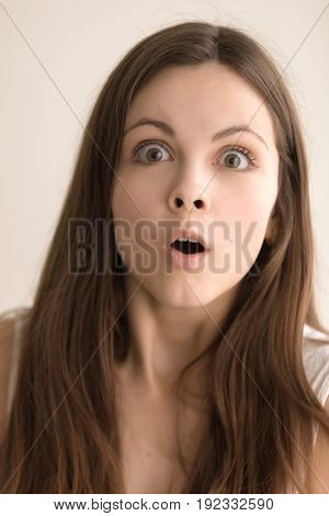 Headshot portrait of scared young woman. Attractive teen girl with shocked facial expression looking at camera with fear. Lady feels terrified or surprised. Amazing news concept. Close up. Front view
