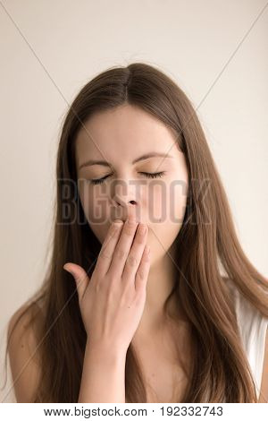 Headshot portrait of sleepy young woman. Tired pretty teen girl yawning with closed eyes. Adorable female feeling lack of sleep, boring during the day, struggling with drowsiness. Close up. Front view