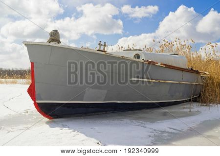 An old motor launch at the sunny winter day on a rushy river.