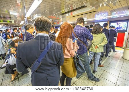 Tokyo, Japan - April 17, 2017: rush hour: crowd of people waiting the Marunouchi Line, subway line in Tokyo at Shinjuku Station. On maps and signboards, the line is shown in red and with the letter M.