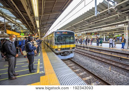 Tokyo, Japan - April 17, 2017: people waiting on tracks of Chuo Line local, for Akihabara, the yellow line of JR Line, a rail service that crosses east-west Tokyo downtown. Shinjuku Station.