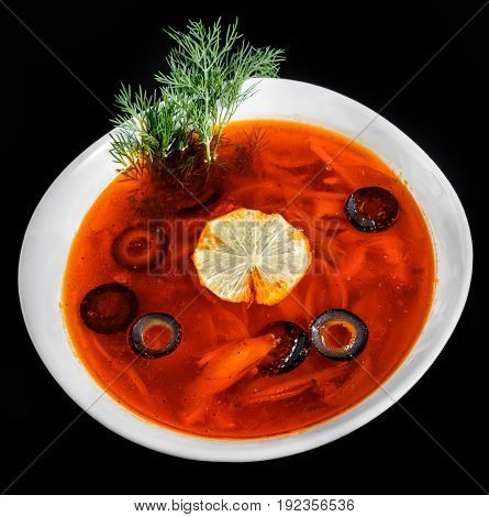 Soup with meat olives herbs and lemon in bowl isolated on black background homemade food. Traditional Russian soup - solyanka. Top view