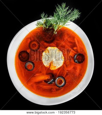 Soup with meat olives herbs and lemon in bowl isolated on black background homemade food. Traditional Russian soup - solyanka. Top view