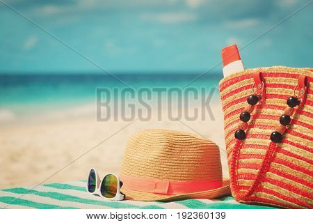 hat, sunglasses and bag with suncream on tropical beach