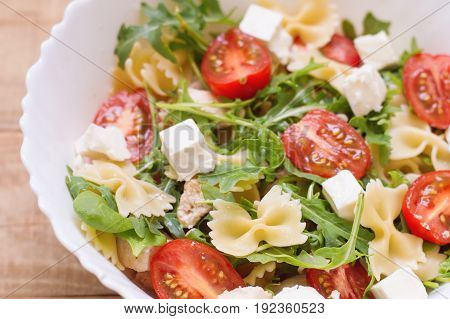Big portion of homemade pasta salad with red cherry tomatoes feta cheese chicken breast baby spinach leaves arugula (rocket leaves) and farfalle. Appetizer. Healthy eating