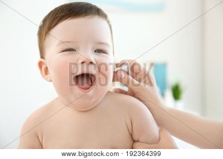 Doctor examining little baby with ear speculum in clinic. Baby health concept
