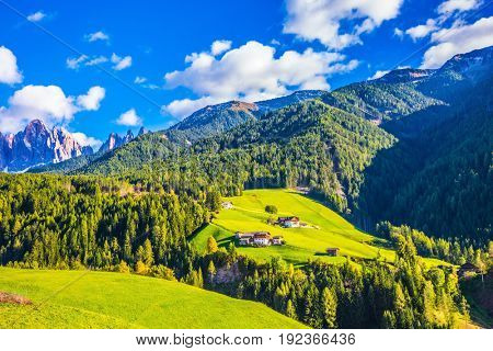 Charming chalet on a green grassy slope. The valley is surrounded by a dentate wall of dolomite rocks. Warm autumn in the Dolomites. The concept of ecological tourism
