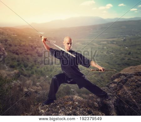 Wushu master with sword, meditation on mountain