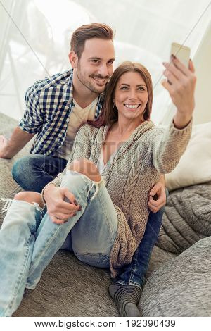 Young attractive couple having fundoing selfie at home.