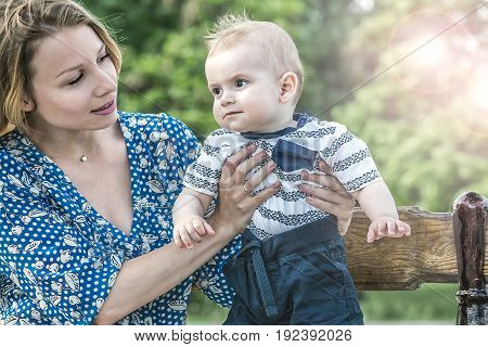 Beautiful happy mather with baby boy outdoor on nature at sunny summer say