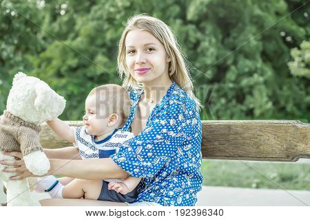 Pretty mather playing with baby boy outdoor on nature at sunny summer day