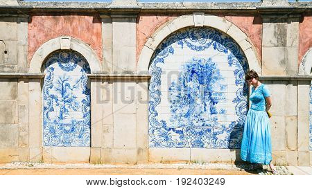 Travel to Algarve Portugal - tourist near outside wall of Estoi Palace with traditional azulejo tile decor in Estoi village. The Palace was built in the late 19th century