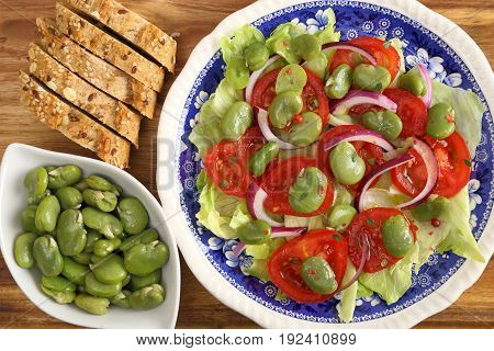 Close up of a broad beans salad with tomato and red onion.
