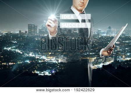 Businessman with document in hand drawing digital business scheme on illuminated night city background. Idea concept. Double exposure