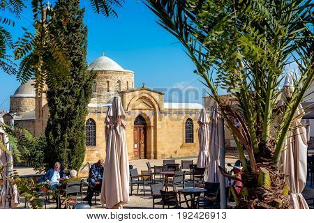Peristerona Cyprus - March 03 2017: People Sitting At Outdoors Cafe Near Apostles Varnavas Church.