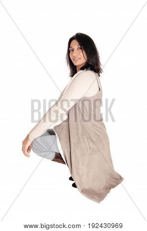 A young Hispanic woman crouching on the floor in a deerskin coat looking into the camera isolated for white background.